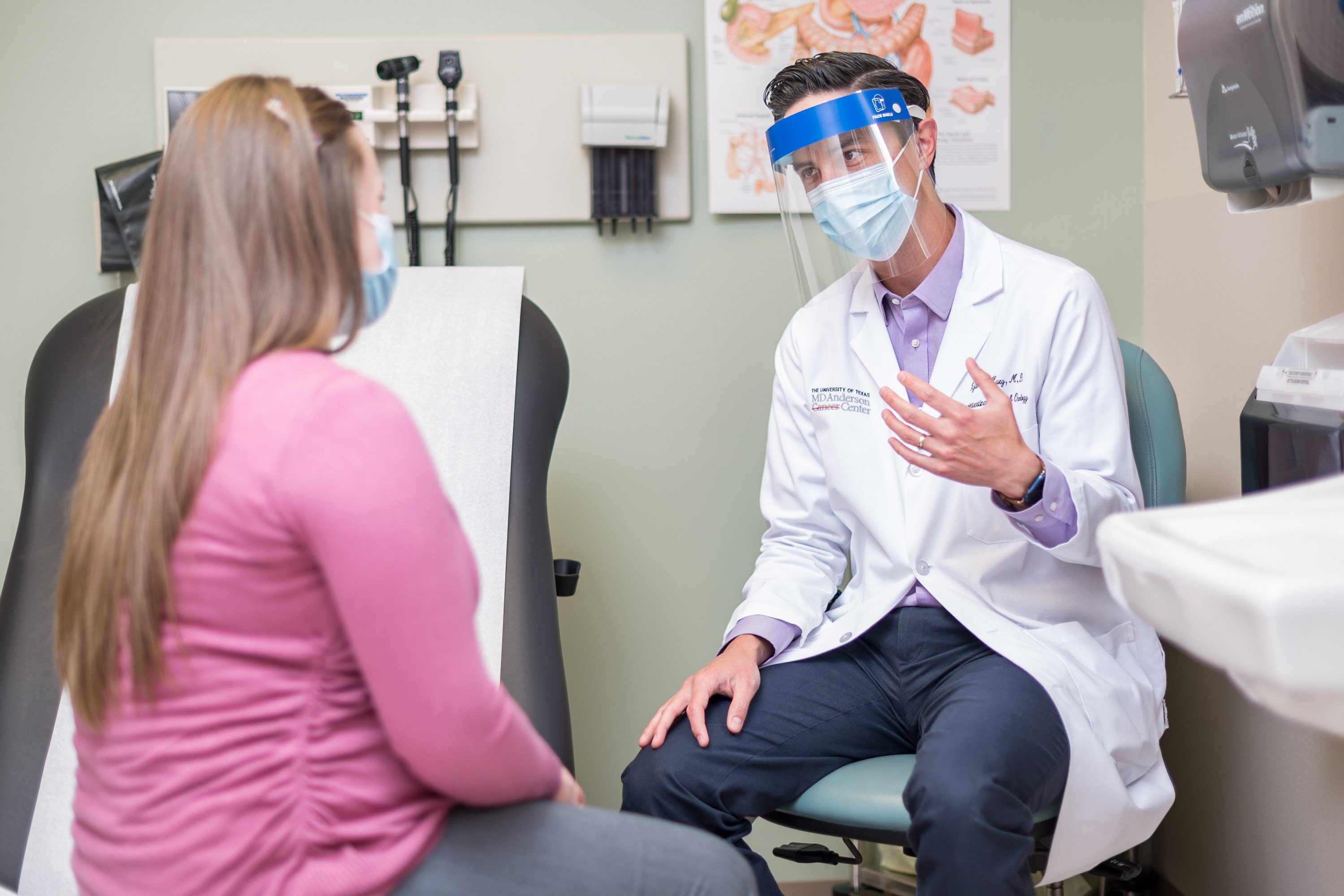 医学博士瑞安·休伊（Ryan Huey）在医疗级面罩上戴着面罩时与病人说话。