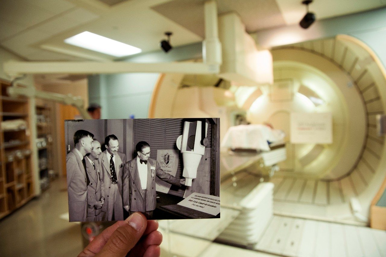 MD安德森的医生们在质子治疗机前观察一个辐照器模型的年代照片。