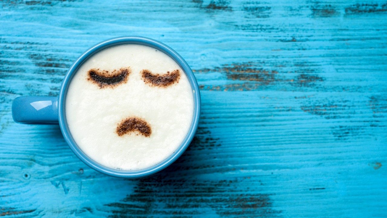咖啡杯用悲伤的表情来描绘抑郁