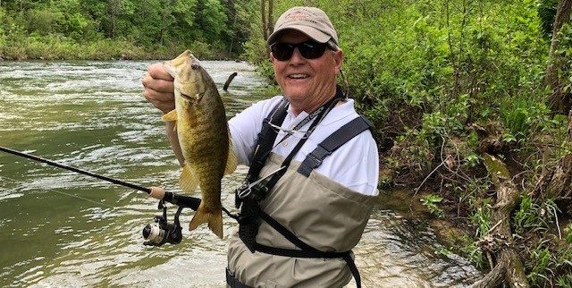 脂肪肉瘤幸存者汤姆Gattle拥有一条鱼，他抓住了，而他的肩膀截肢后钓鱼。