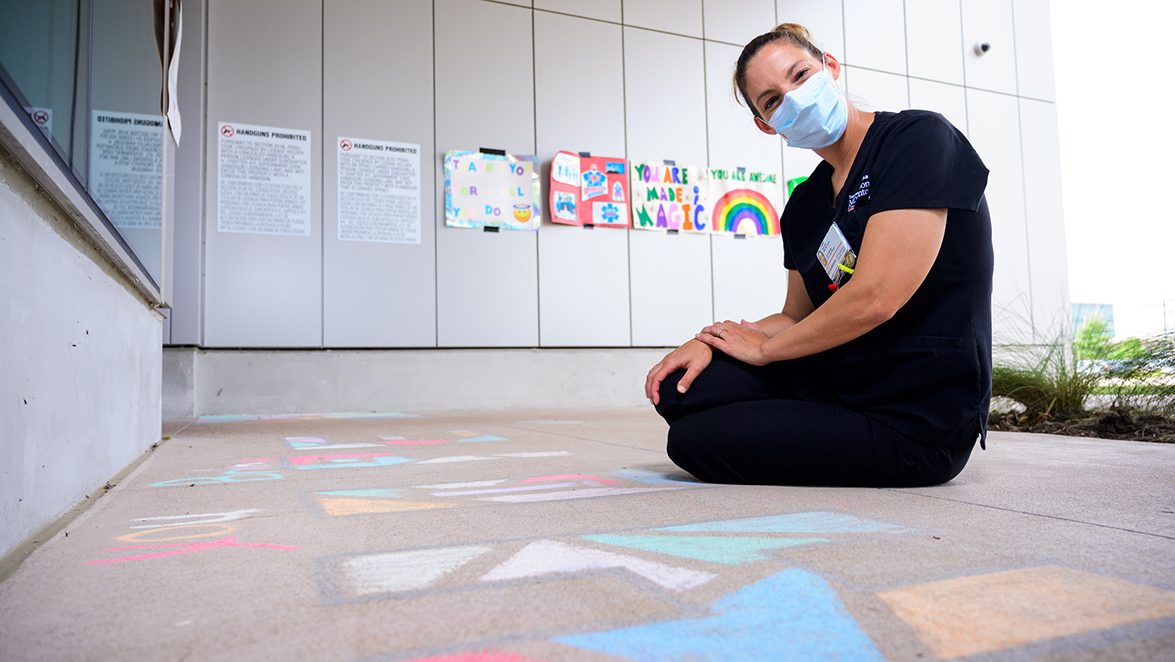 MD安德森西休斯顿护士娜塔莉·桑切斯坐在癌症患者创造粉笔艺术，她和她的团队旁边的地面