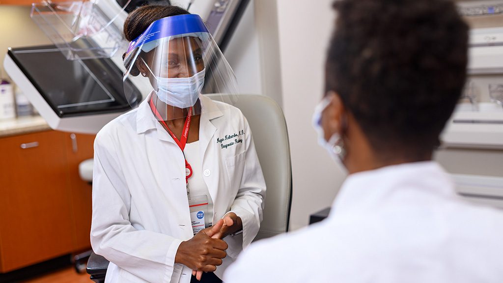 医学博士蒂莫西·雅普戴着口罩与病人交谈