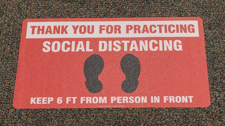 MD Anderson的地板上挂着红色贴纸，上面写着社交距离提醒