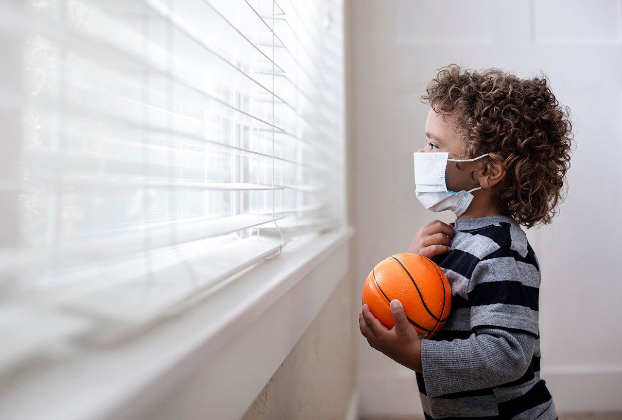 孩子戴着面具，拿着篮球，看着窗外