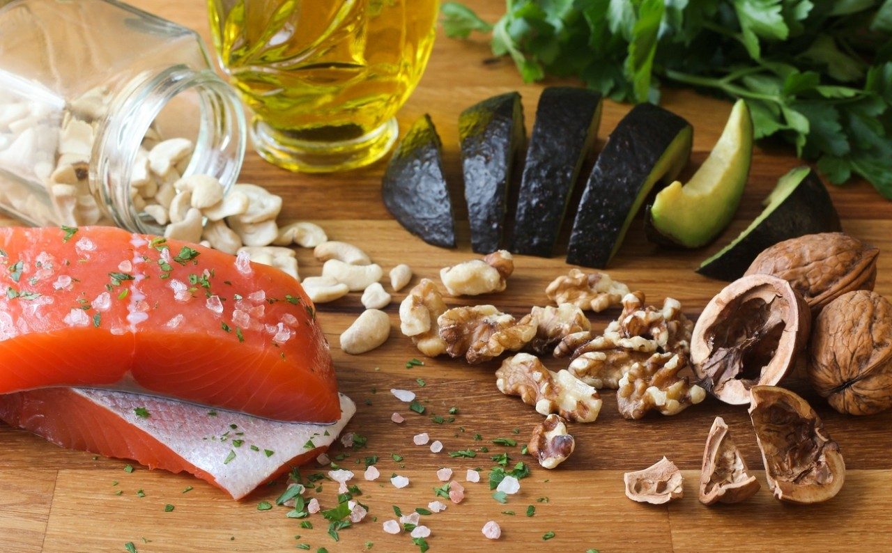地中海饮食中的一些成分显示在一块板上:鲑鱼、核桃、橄榄油和鳄梨。