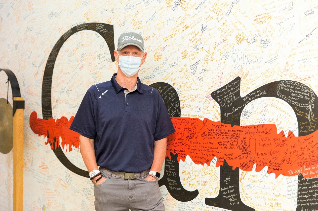 在完成睾丸癌治疗后，查克·威廉姆斯站在MD安德森质子治疗中心的锣旁。