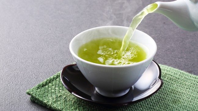 绿茶被倒进茶杯中。