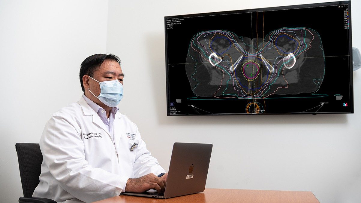 Cullen Taniguchi, M.D, Ph.D.，正在检查从他的笔记本电脑投射到墙上监控器上的肛门癌扫描图。