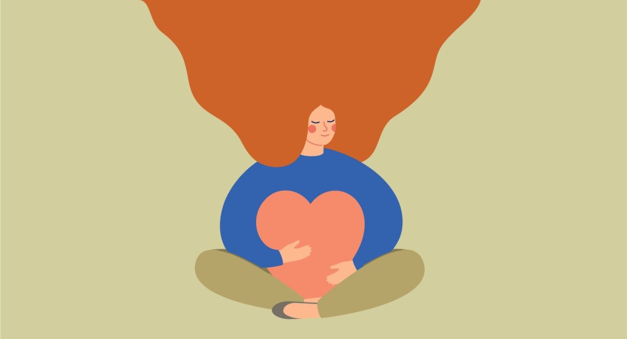 说明女人的橙色头发和蓝色衬衫坐在地上,拥抱一个粉红色的心。