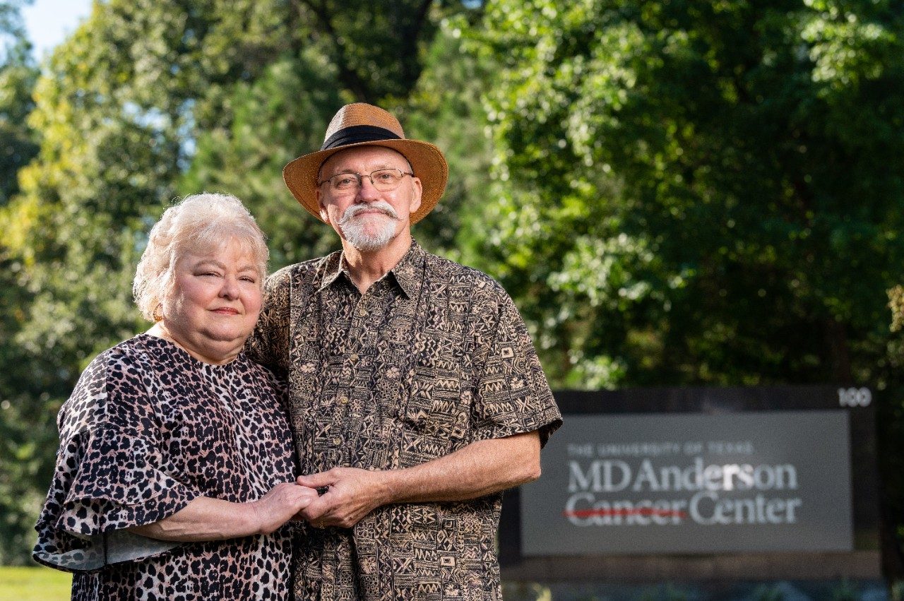 乳腺癌幸存者Teresa和Billy Mayo手牵着手站在MD Anderson癌症中心的标志旁边。