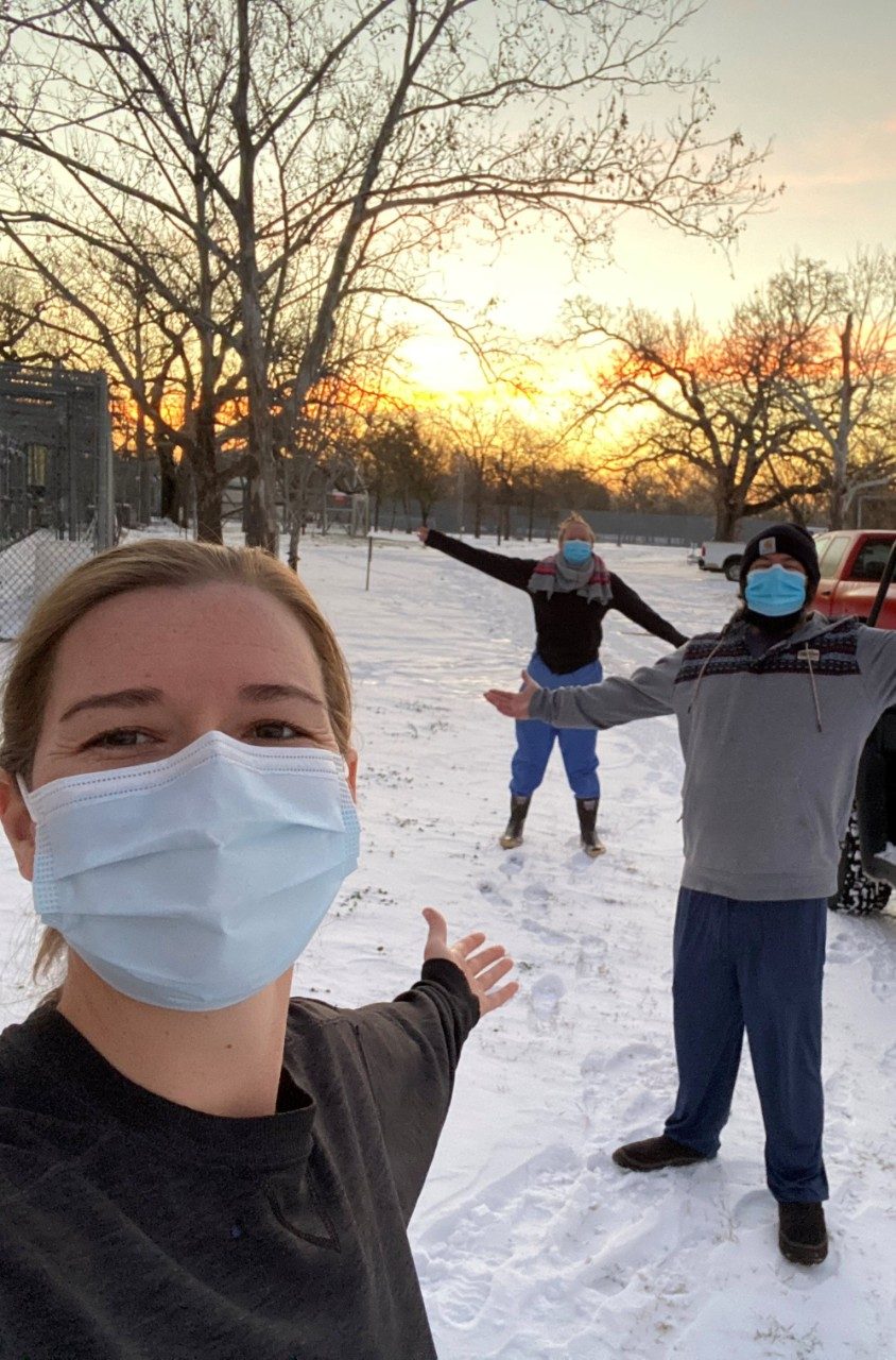 三名脸口罩的工作人员在雪地里站在外面