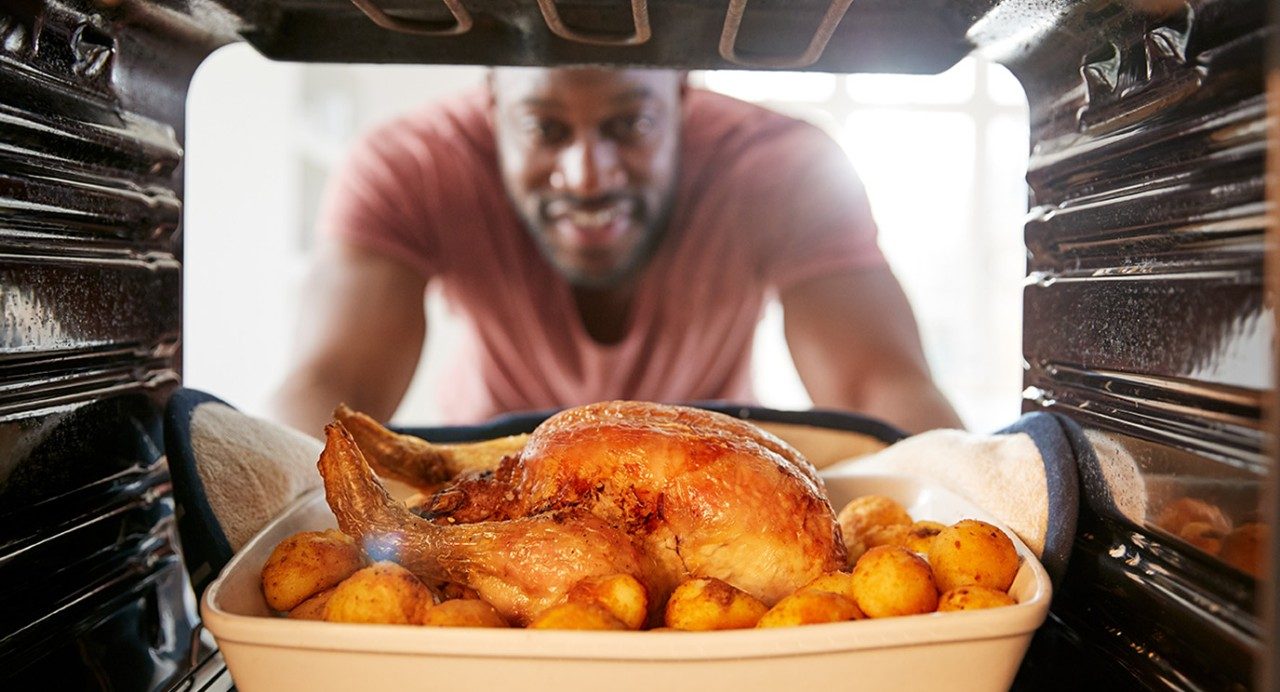 Man places roast chicken in the oven