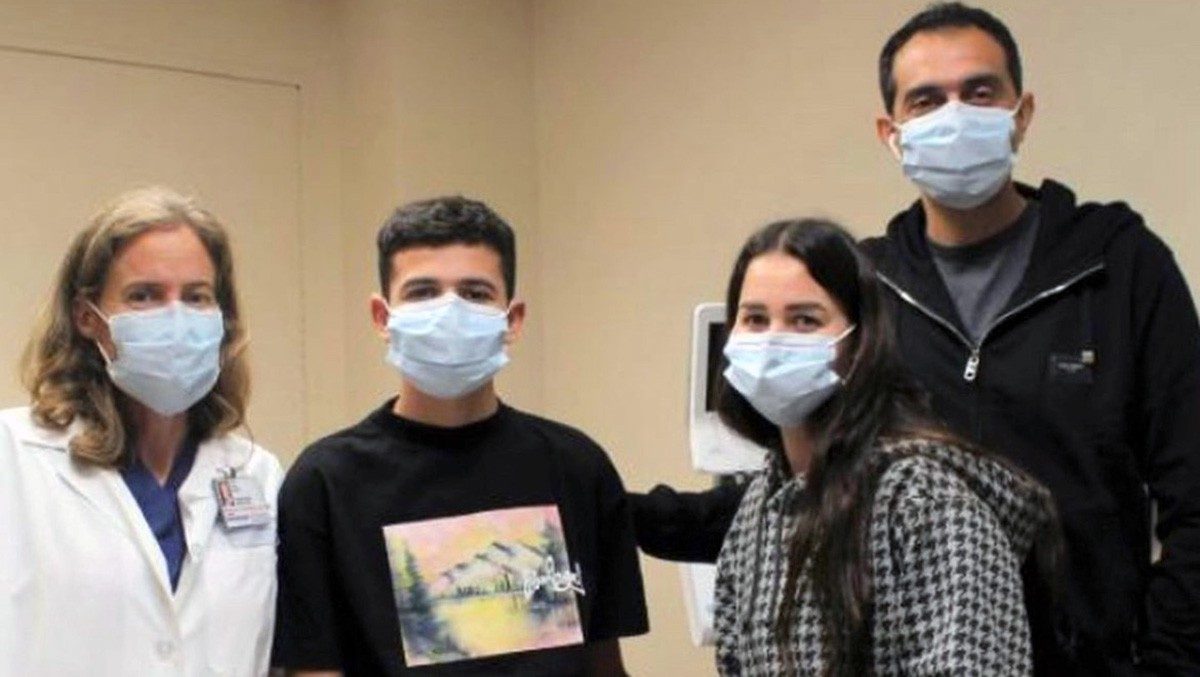阿巴斯Nadim站和他的父母,随着玛丽·奥斯汀,医学博士,在左边。都是戴医用口罩。