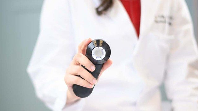 腰际的医生拿着dermoscope伸出的手