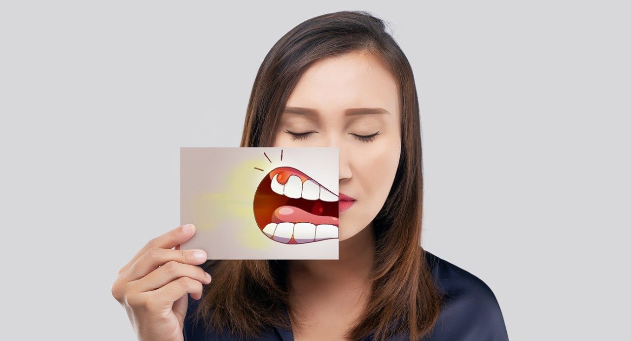 年轻人闭着眼睛拿着画卡通口香糖癌症在她面前的嘴