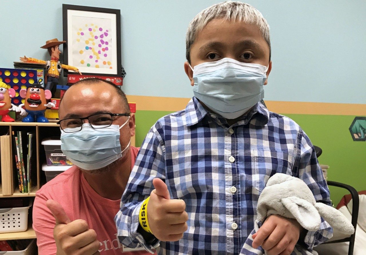 小儿脑瘤幸存者本Gadot给大拇指站在面前的儿童生活专家莱昂Benavides安德森质子治疗中心。