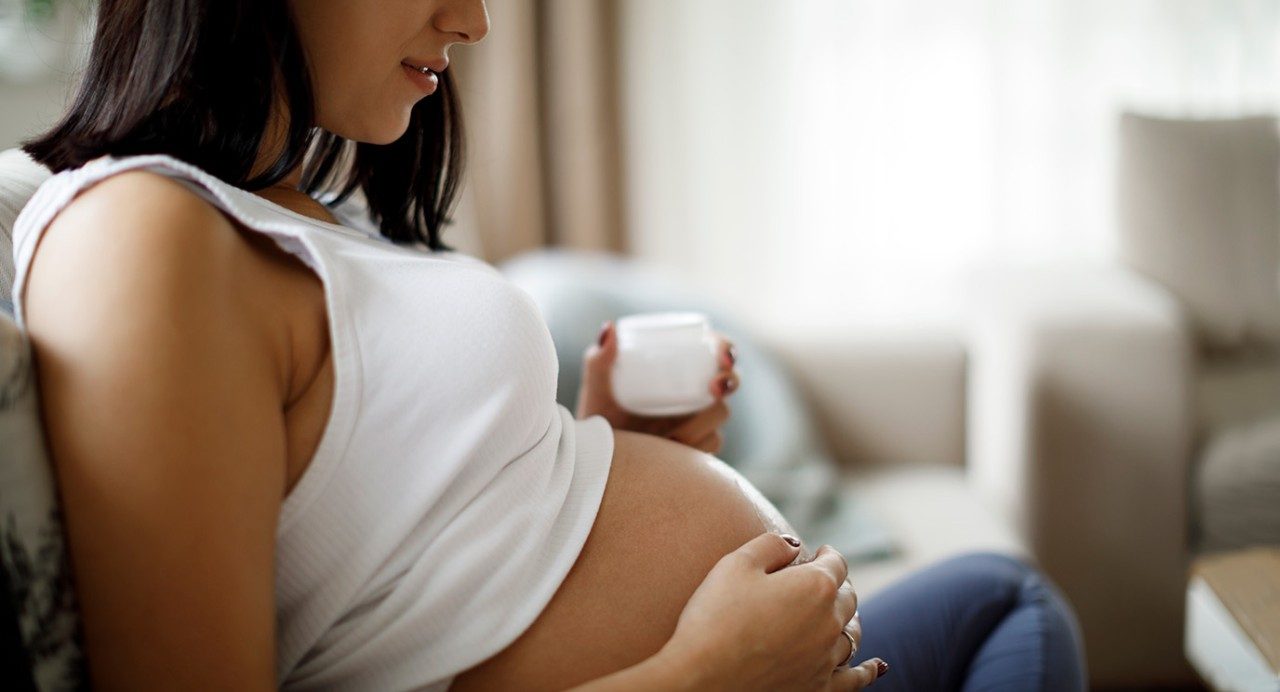 Pregnant person looking at her belly.