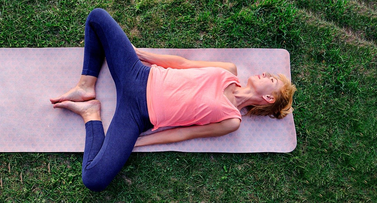 图片显示一个女人躺在瑜伽垫上伸展双腿