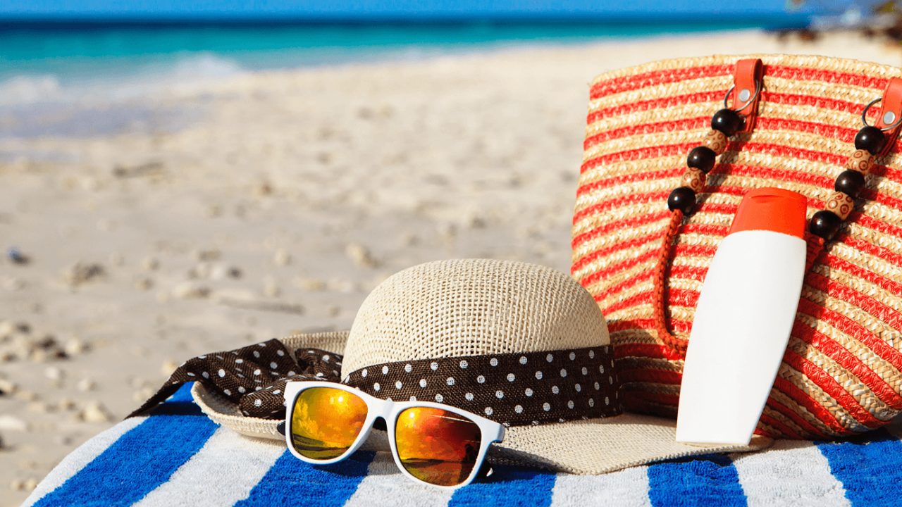 帽子，太阳镜和沙滩包在沙滩上的毛巾