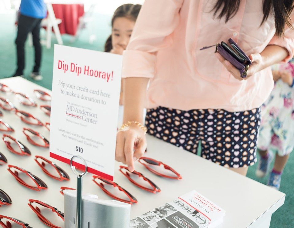 At the MD Anderson Pavilion, fans enjoy the opportunity to pick up a pair of sunglasses and make a credit card donation to help end cancer. Photo by Adolfo Chavez III