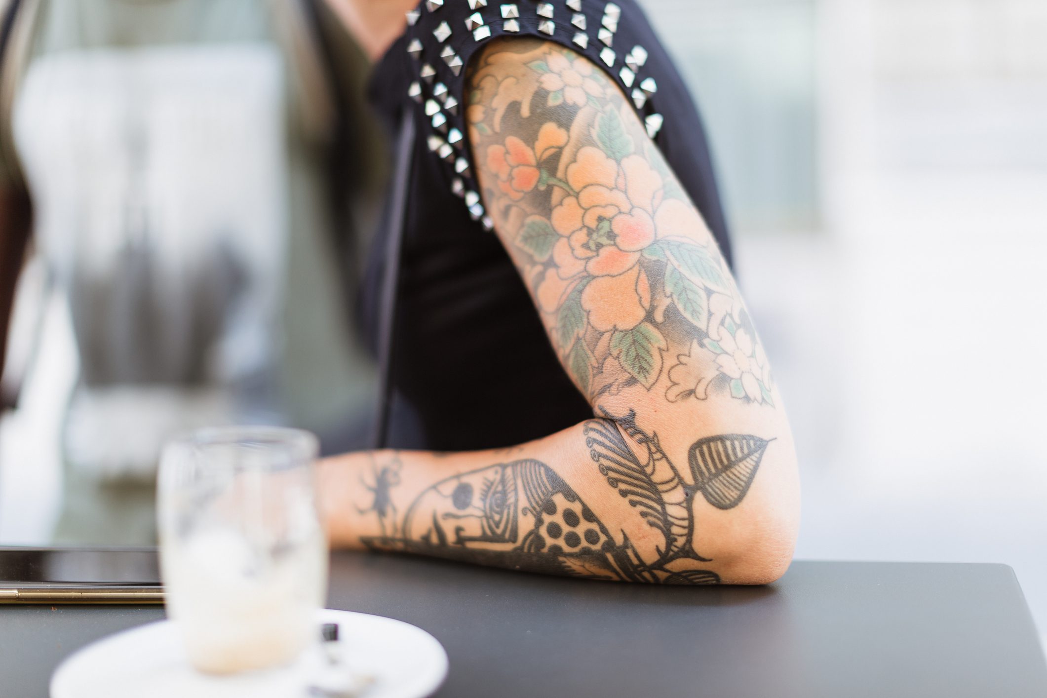 纹身的女人胳膊坐在一张桌子和咖啡